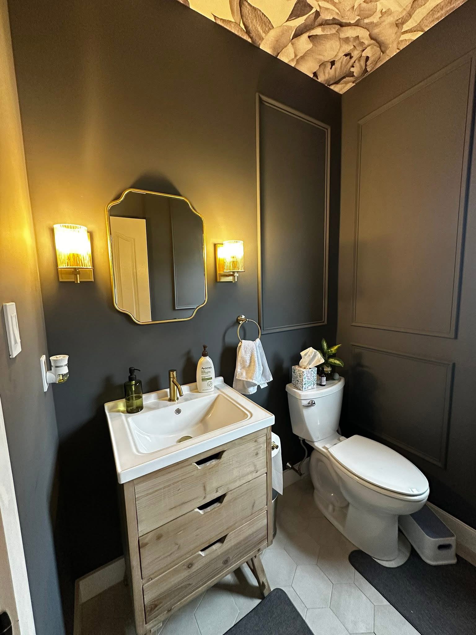 Moody powder room with floral ceiling and gold fixtures