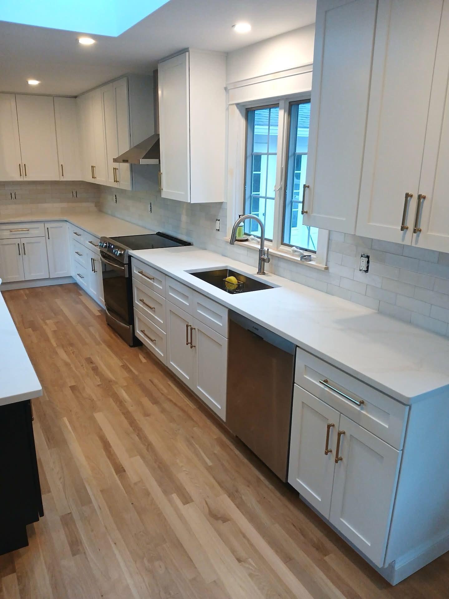 White kitchen with wood island and skylight