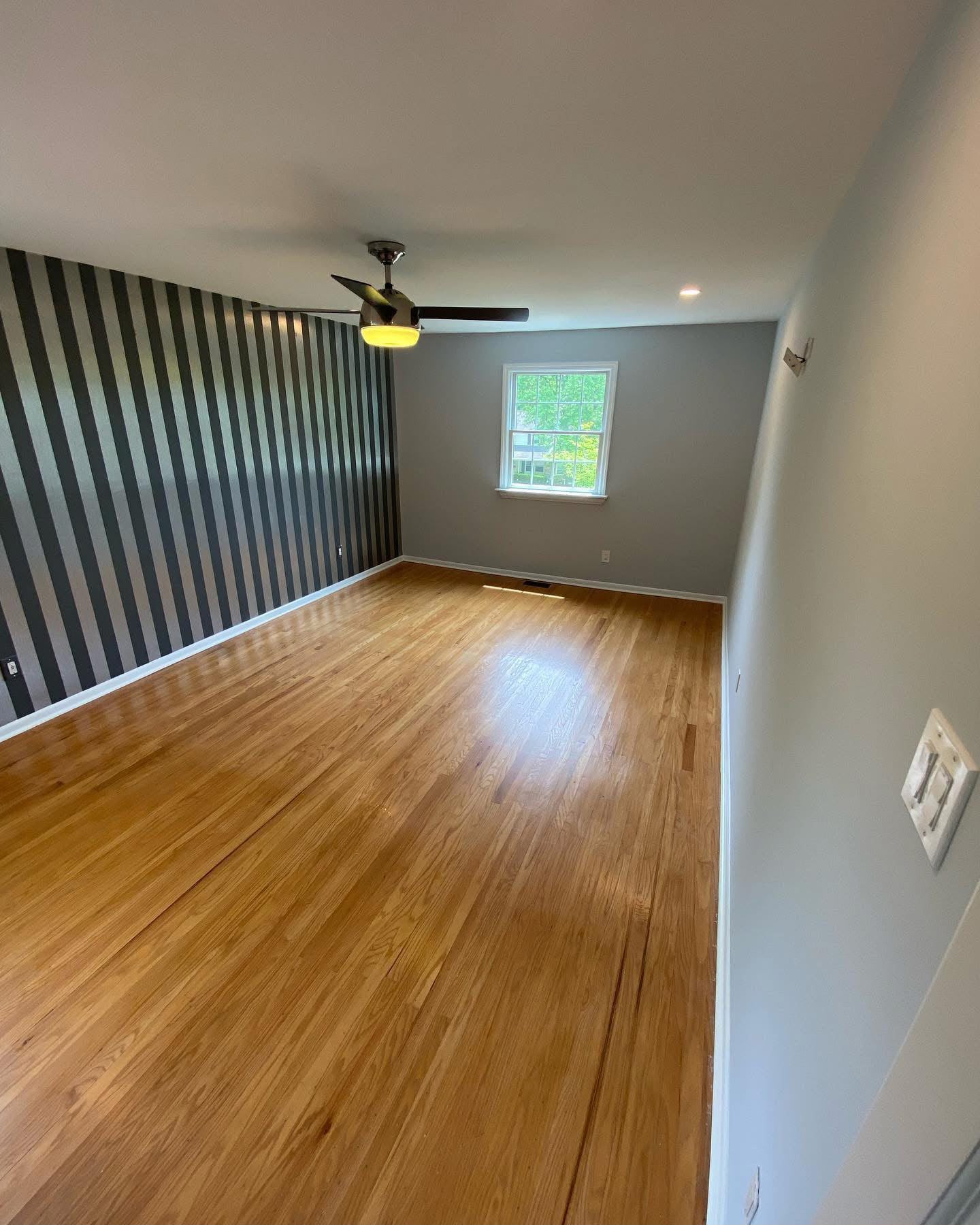 Room with striped accent wall and hardwood flooring